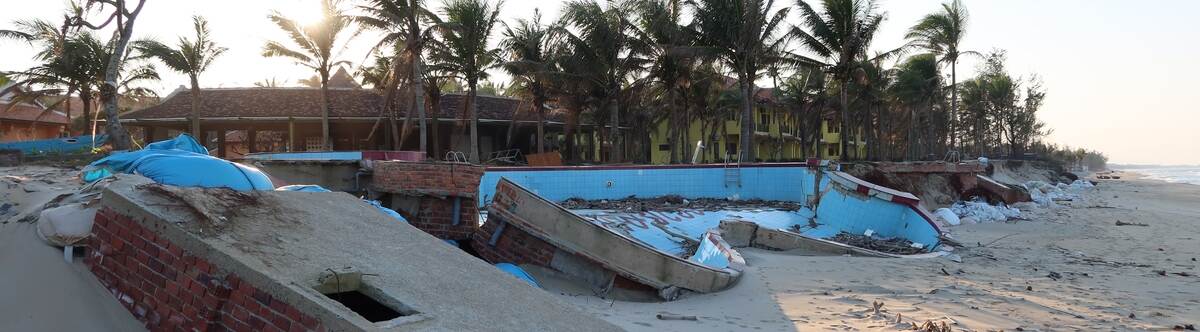 A collapsed frontal wall of a building on the coast of Hoi An lies on the sand, broken and dilapidated